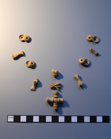 Erhaltene Reste eines Rosenkranzes aus einem neuzeitlichen Grab: geschnitzte Miniaturanhänger der Fünf-Wunden-Christi aus Bein. (IN TERRA VERITAS)